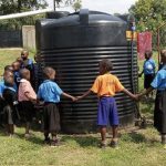 school children around a water harvesting tank