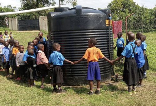 school children around a water harvesting tank